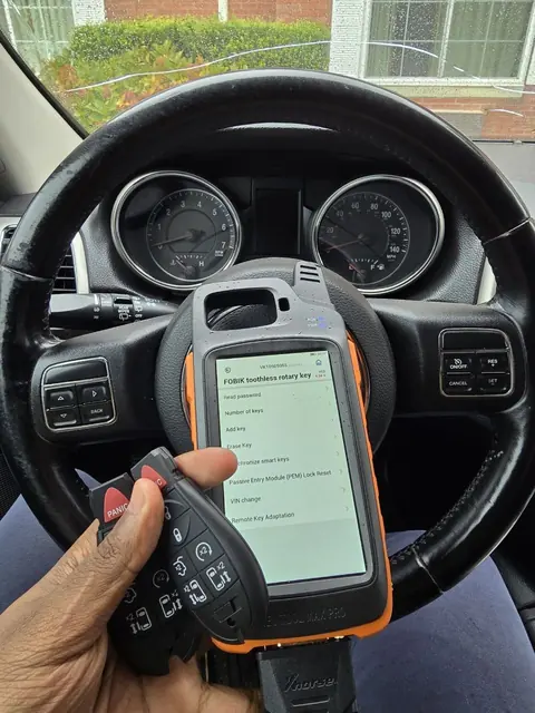 Key programming tool on a steering wheel next to new key fobs